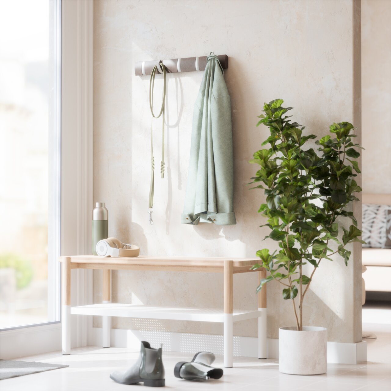 Umbra Wandkapstok FLIP Wandgarderobe mit Haken, an der ein grüner Mantel und eine Leine hängen, daneben eine Bank mit Kopfhörern und einer Trinkflasche, im Vordergrund ein Paar Stiefel und eine grüne Pflanze im Topf, seitliche Perspektive.