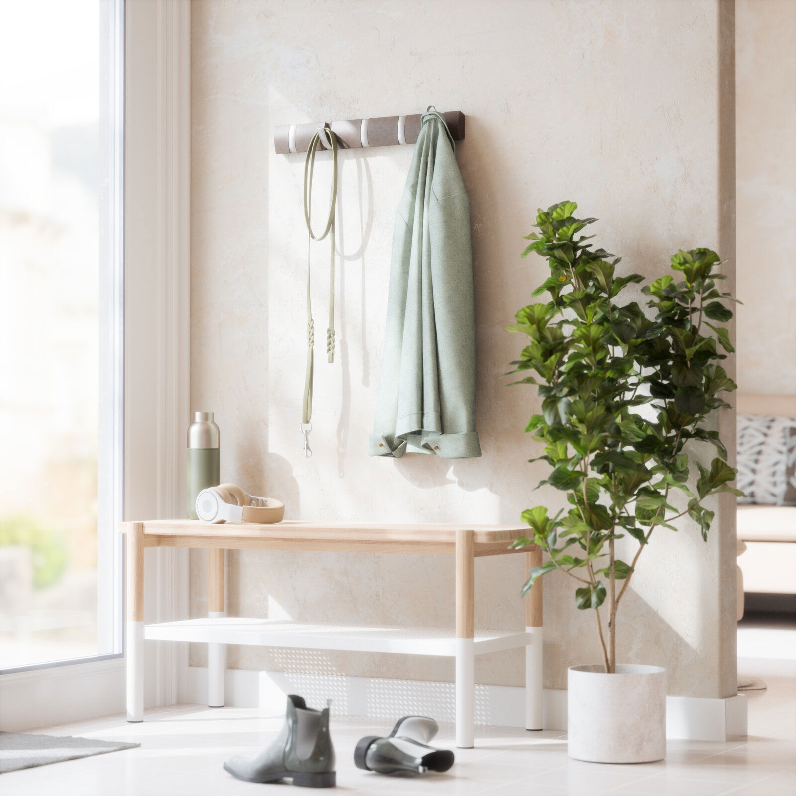 Umbra Wandgarderobe FLIP Wandgarderobe mit Haken, an der ein grüner Mantel und eine Leine hängen, daneben eine Bank mit Kopfhörern und einer Trinkflasche, im Vordergrund ein Paar Stiefel und eine grüne Pflanze im Topf, seitliche Perspektive.