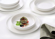 Elegantes Gourmet-Set mit weißen Tellern und Schalen, präsentiert mit einer stilvollen Pasta-Garnitur, aus der Vogelperspektive fotografiert.