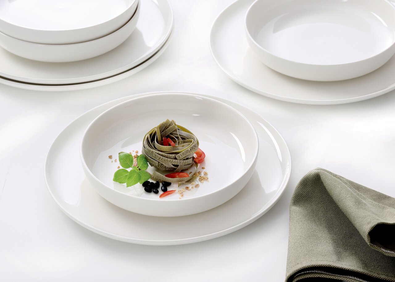 Elegantes Gourmet-Set mit weißen Tellern und Schalen, präsentiert mit einer stilvollen Pasta-Garnitur, aus der Vogelperspektive fotografiert.