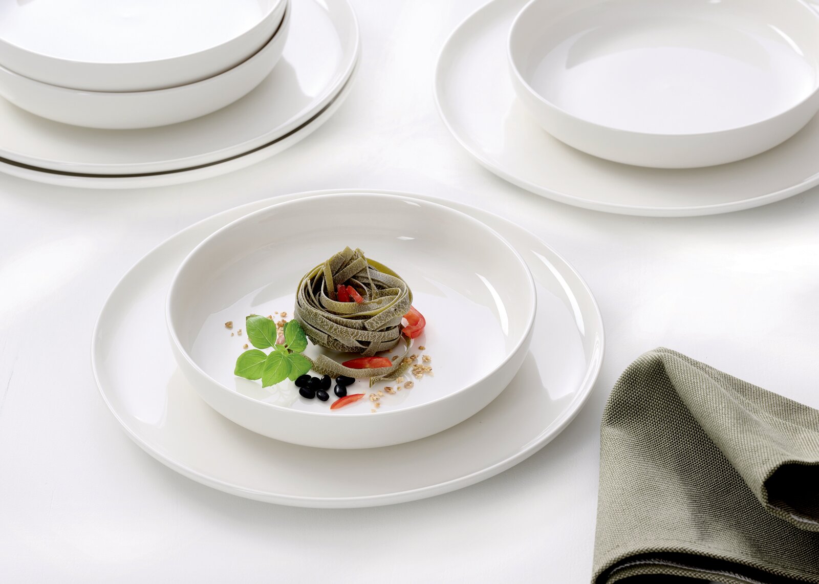 Elegantes Gourmet-Set mit weißen Tellern und Schalen, präsentiert mit einer stilvollen Pasta-Garnitur, aus der Vogelperspektive fotografiert.
