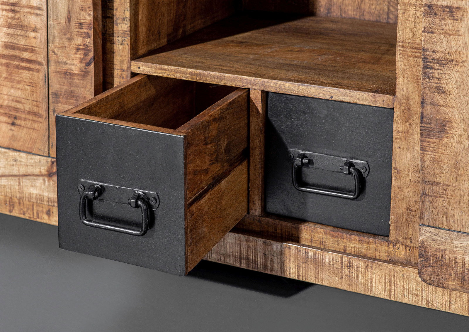 Nahaufnahme eines rustikalen Sideboards aus Holz mit zwei schwarzen Schubladen, eine davon geöffnet, aus seitlicher Perspektive.
