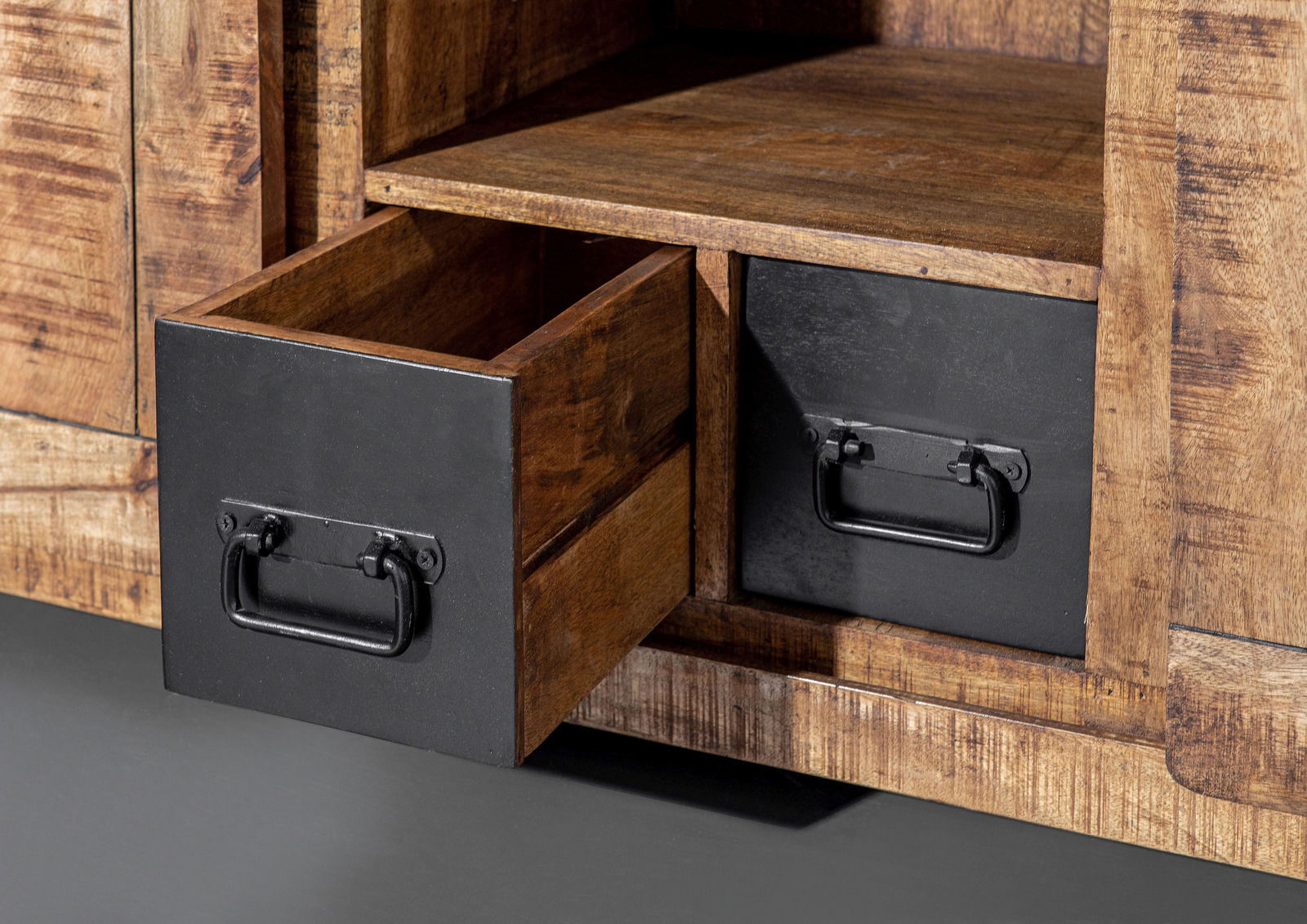 Nahaufnahme eines rustikalen Sideboards aus Holz mit zwei schwarzen Schubladen, eine davon geöffnet, aus seitlicher Perspektive.