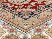 Nahaufnahme eines Orientteppichs mit komplexen floralen Mustern in Rot, Blau, Beige und Weiß, schräg von oben fotografiert.