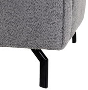 Nahaufnahme einer grauen, strukturierten Sofaecke mit schwarzen Metallbeinen, seitliche Perspektive.