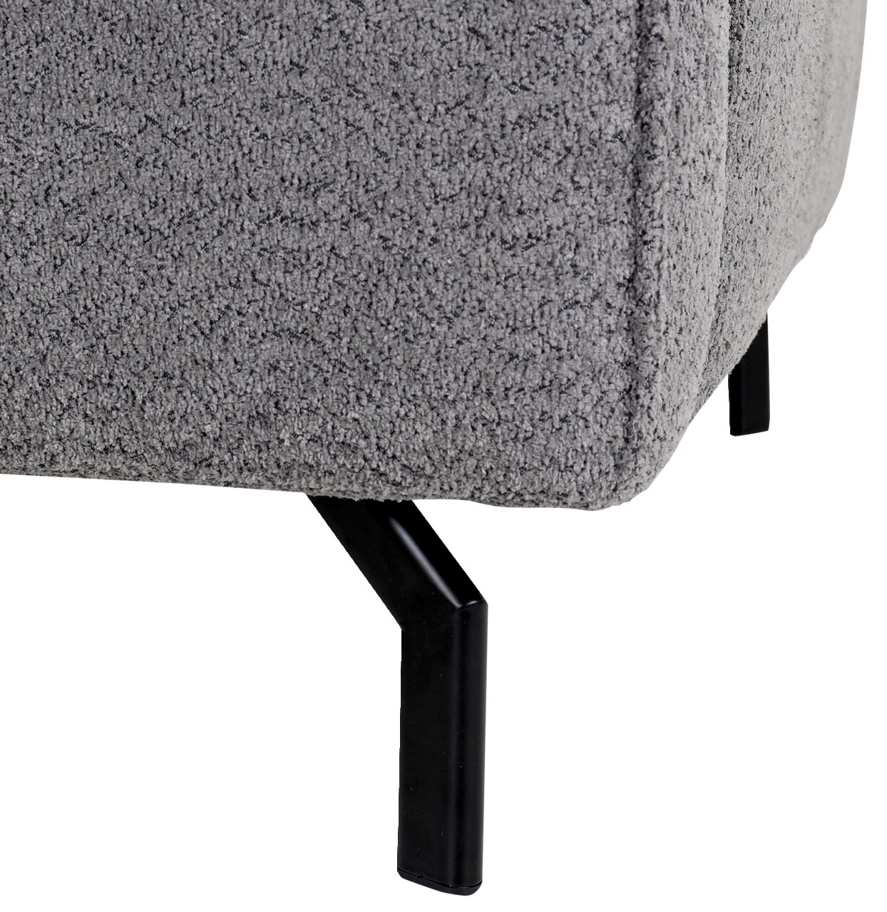 Nahaufnahme einer grauen, strukturierten Sofaecke mit schwarzen Metallbeinen, seitliche Perspektive.