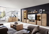 Moderne Wohnzimmermöbel aus Holz, bestehend aus Wohnwand, Sideboard, Vitrine und Couchtisch, in einem hellen Raum mit großen Fenstern, seitliche Perspektive.