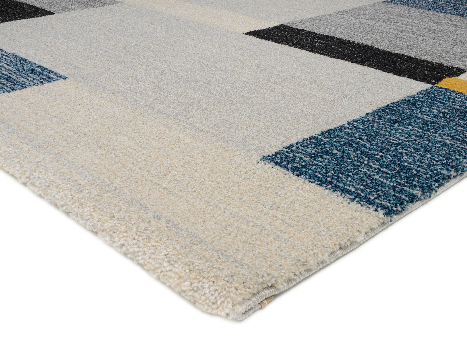 Nahaufnahme eines Frisé-Teppichs mit geometrischem Muster in Blau-, Grau- und Beigetönen, perspektivisch von der Seite aufgenommen.