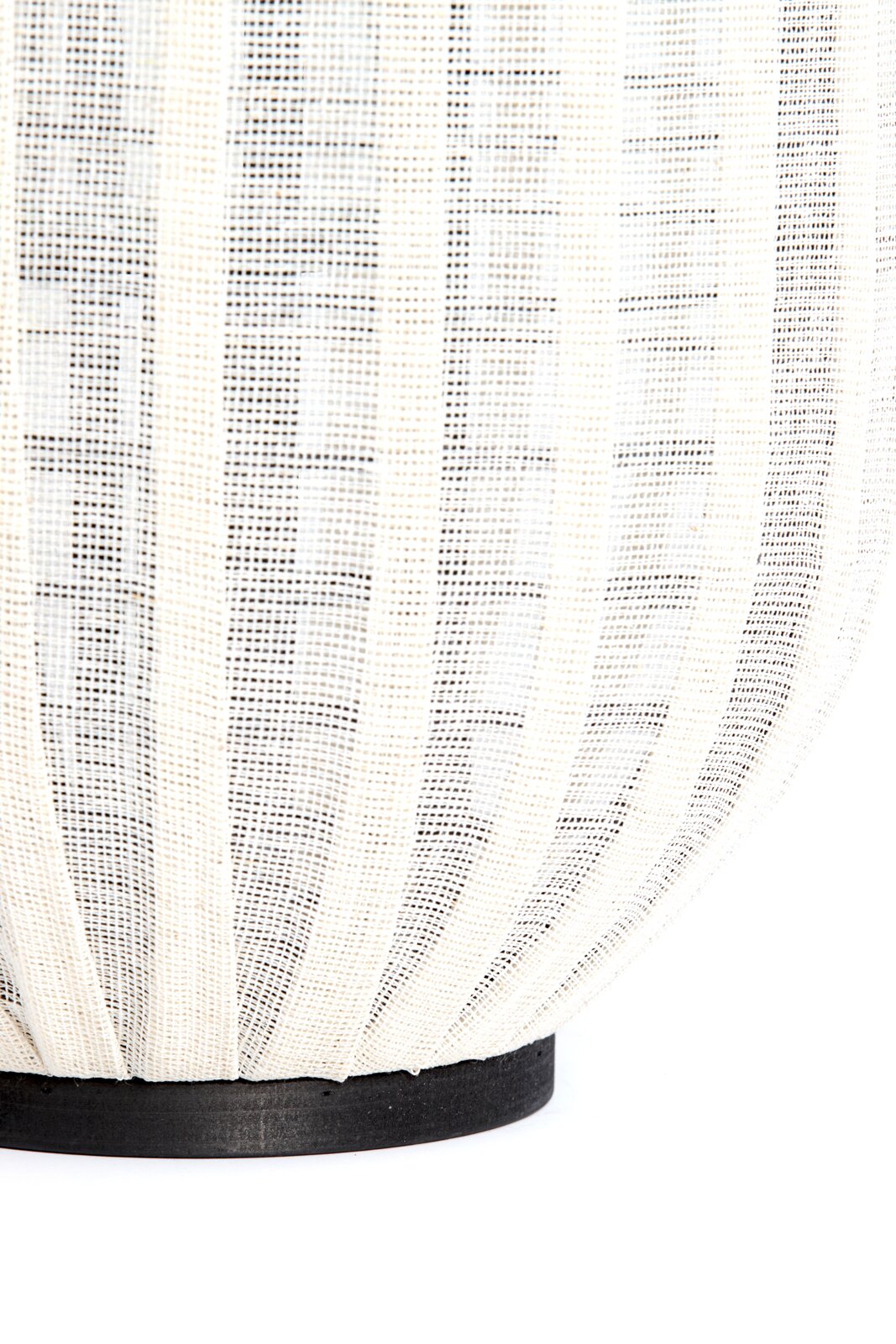 Detailopname vanuit zijaanzicht van een crèmekleurige lamp met geplooid opengeweven textiel en een ronde zwarte voet