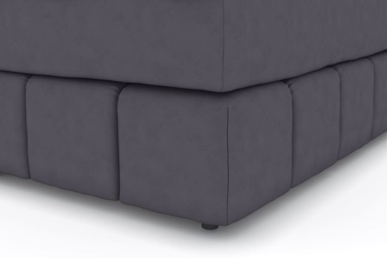Close-up van de hoek van een donkergrijs boxspringbed, gezien van onderaf.