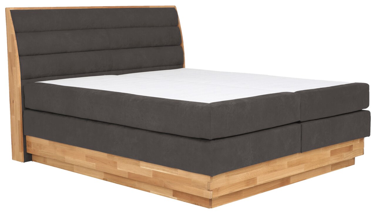 Boxspringbett mit grauem Polster und Holzrahmen, seitliche Perspektive