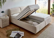 Beiges Polsterbett mit hochgeklappter Matratze und Stauraum, seitliche Perspektive