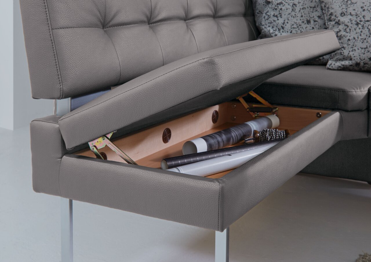 Dieter Knoll Eckbank LIMONE Graue Eckbank mit Stauraum, geöffneter Sitz zeigt Innenraum mit Rollen und Bürsten, seitliche Perspektive