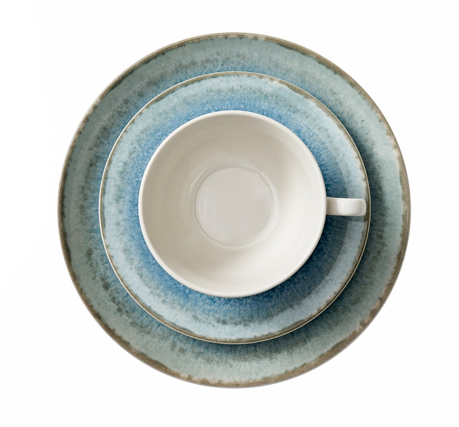 Weiße Kaffeetasse auf blau melierten Keramiktellern im rustikalen Look, Draufsicht von oben