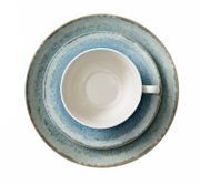Weiße Kaffeetasse auf blau melierten Keramiktellern im rustikalen Look, Draufsicht von oben