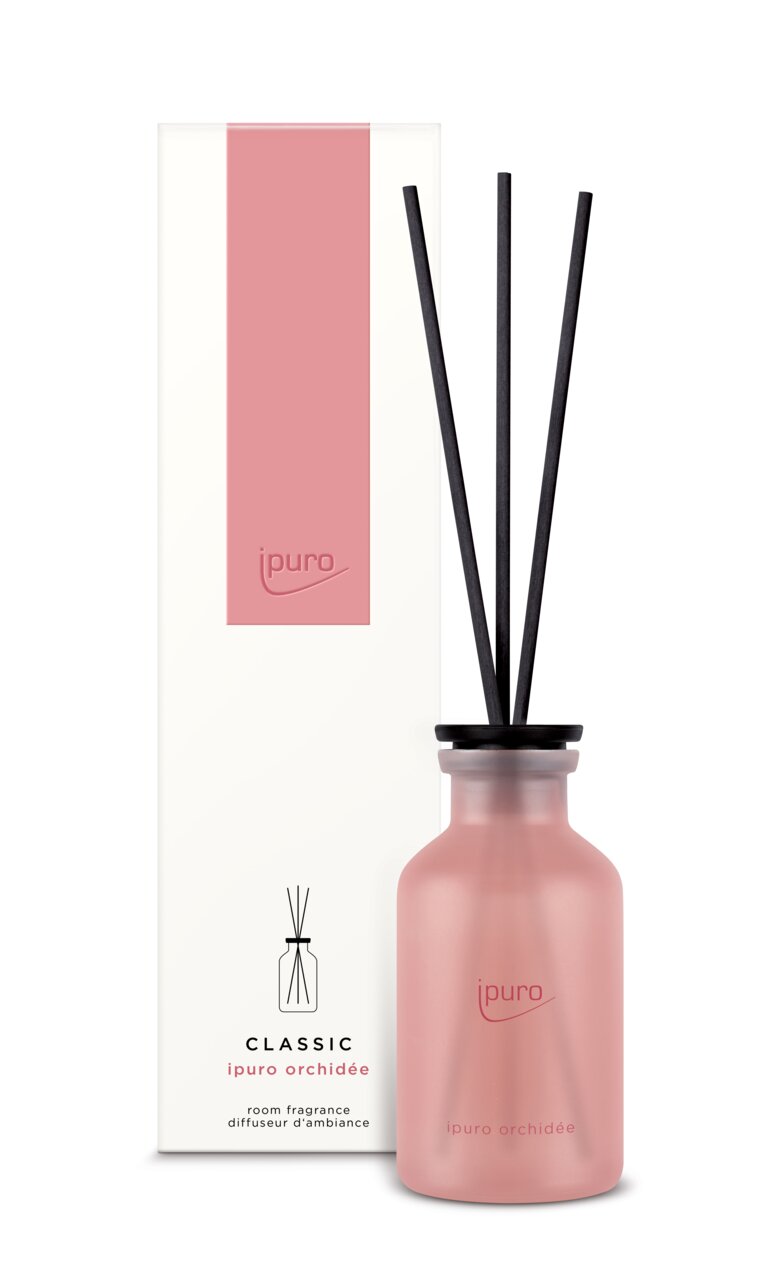 Raumduft Classic Orchidee von ipuro in einer rosa Flasche mit schwarzen Duftstäbchen, frontal abgebildet vor der Verpackung.