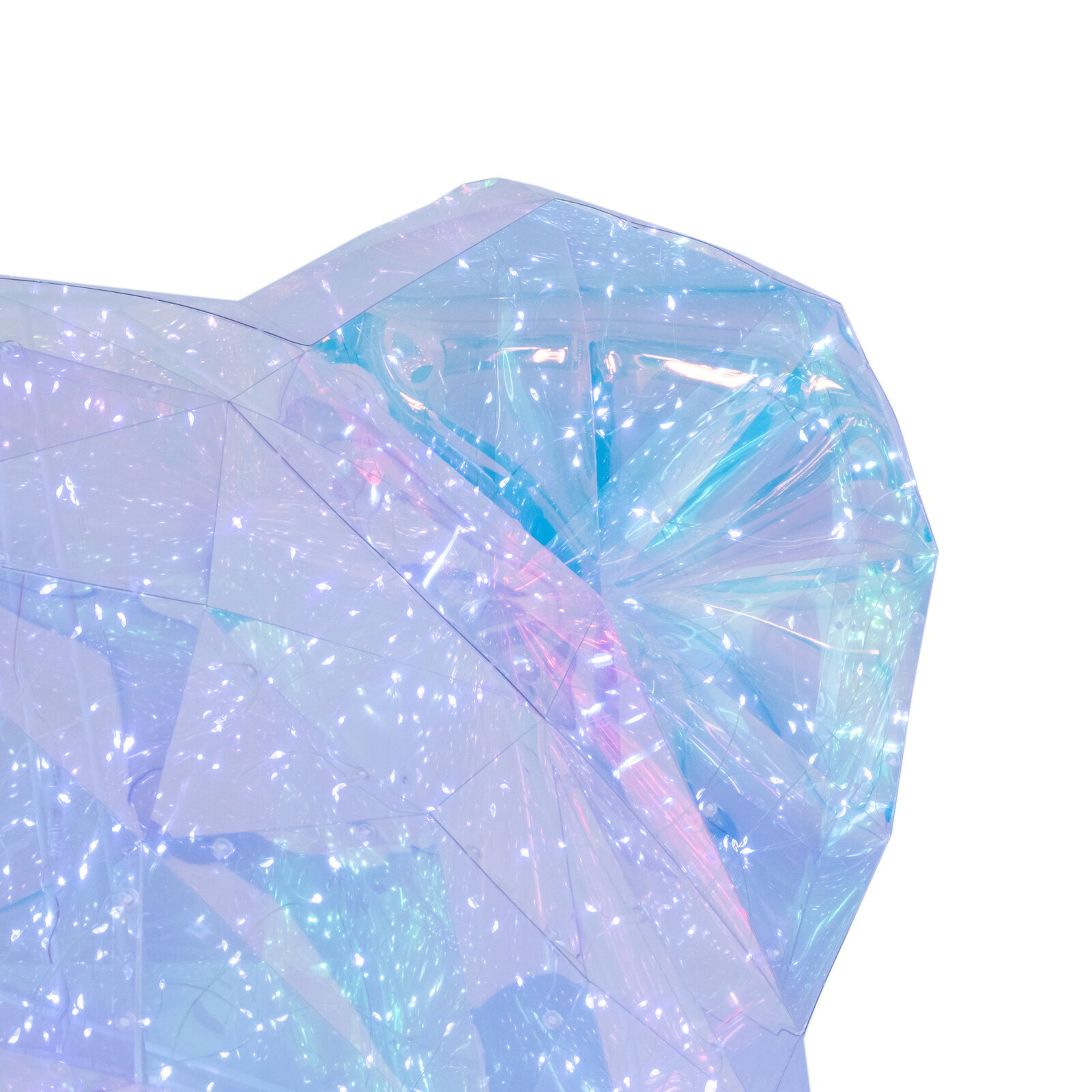 Nahaufnahme eines transparenten, facettierten Deko-Objekts mit irisierendem Blau‑Rosa-Schimmer und glitzernden Lichtreflexen vor weißem Hintergrund, Perspektive: schräg von oben/seitlich.