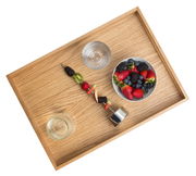 Holztablett aus Eiche mit einer Schale voller Beeren, einem Glas Wasser und einem Fruchtspieß, aus der Vogelperspektive.