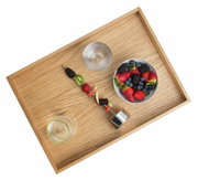Houten dienblad van eikenhout met een schaal vol bessen, een glas water en een fruitspies, gezien vanuit vogelperspectief.