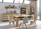 Moderne Esszimmermöbel aus Holz mit Tisch, Stühlen, Sideboard und Vitrine in einem hellen Raum mit großen Fenstern, seitliche Perspektive.