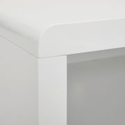 Nahaufnahme einer Ecke eines weißen TV-Lowboards mit abgerundeten Kanten, Perspektive von oben.