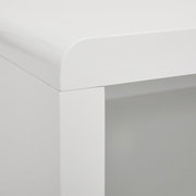 Nahaufnahme einer Ecke eines weißen TV-Lowboards mit abgerundeten Kanten, Perspektive von oben.