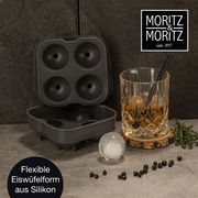 Runde Silikon-Eiswürfelform in geöffneter Perspektive neben einem Glas mit Getränk und einer runden Eiskugel.