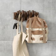 Wandgarderobe aus Holz mit mehreren Haken, an der ein Rucksack, eine Tasche und Schlüssel hängen, aus der Vorderansicht fotografiert.