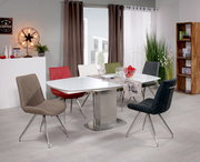 Moderner Esstisch mit weißer Tischplatte und sechs bunten Stühlen in einem stilvoll eingerichteten Esszimmer, seitliche Perspektive.