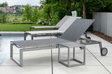 Moderne Rollenliege aus Metall mit verstellbarer Rückenlehne, seitliche Perspektive, auf einer Terrasse neben einem Pool mit grüner Landschaft im Hintergrund.