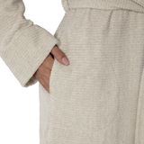 Nahaufnahme eines beigen Kapuzenbademantels in Größe L mit einer Hand in der Tasche, seitliche Perspektive.