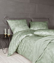 Grünes Mako-Satin Bettwäsche-Set mit floralem Muster auf einem Bett, seitliche Perspektive