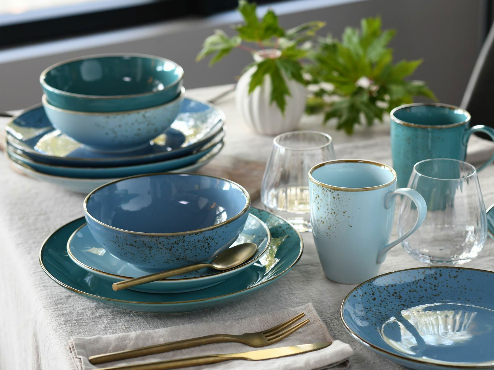 Creatable Kombiservice 16-tlg. NATURE COLLECTION AQUA Elegantes 16-teiliges Kombiservice 'Nature Aq' in Blau- und Grüntönen, bestehend aus Tellern, Schalen und Tassen, auf einem gedeckten Tisch von schräg oben fotografiert.