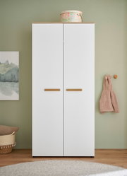 Weißer zweitüriger Kleiderschrank mit Holzgriffen und Holzdeckplatte, frontal von vorn in einem Raum mit grüner Wand aufgenommen.