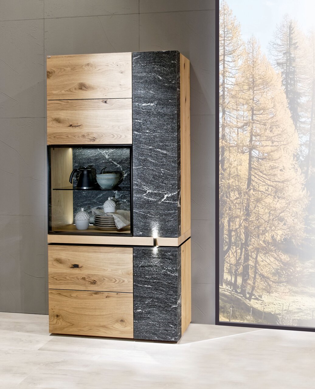 Moderne Vitrine aus Holz und Steinoptik, frontal fotografiert, mit Glaseinsatz und dekorativen Gegenständen.