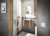 Modernes Gästebad mit hängendem Waschtisch aus Holzoptik, schwarzem Wasserhahn und großem Spiegel, seitliche Perspektive.