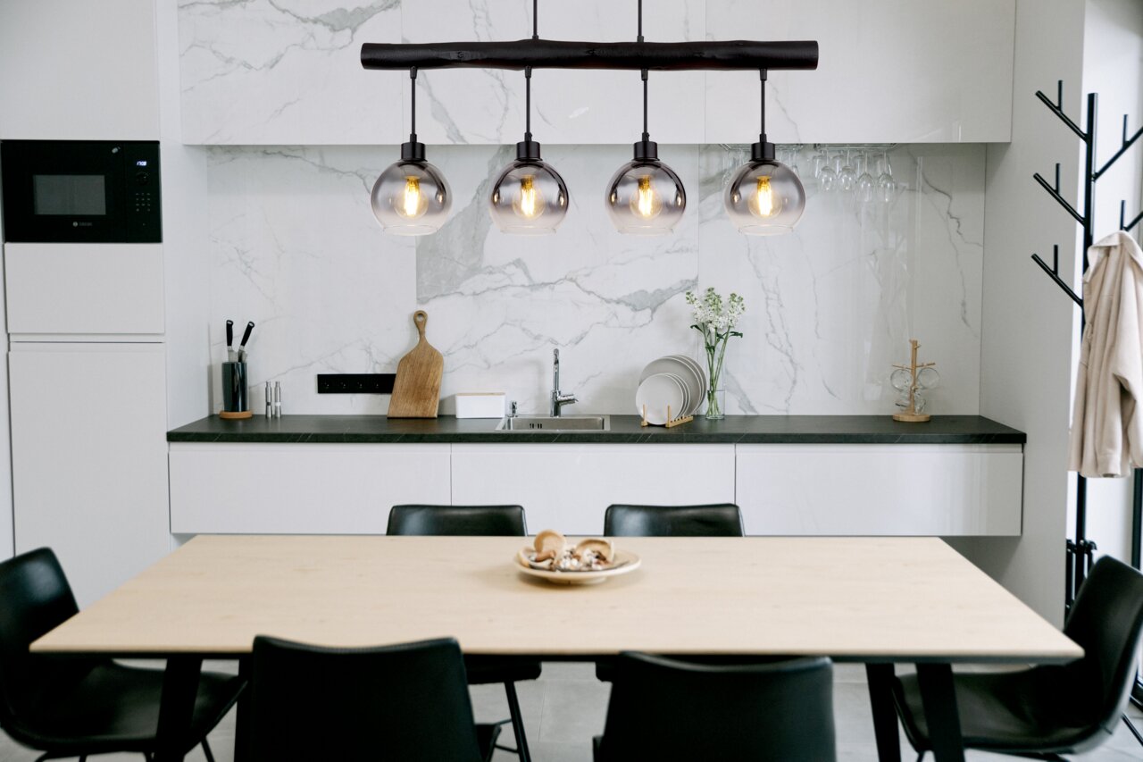 Globo Lighting Hängeleuchte MOITAS Moderne Hängeleuchte mit vier Glaskugeln über einem Esstisch in einer stilvollen Küche, seitliche Perspektive.
