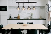 Moderne Hängeleuchte mit vier Glaskugeln über einem Esstisch in einer stilvollen Küche, seitliche Perspektive.