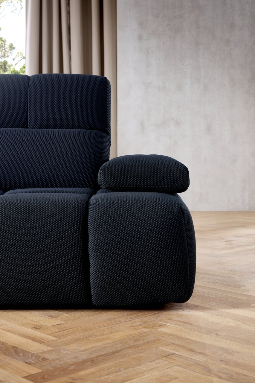 Close-up van een moderne, donkergrijze hoekbank met gestructureerde stoffen bekleding, gezien vanaf de zijkant