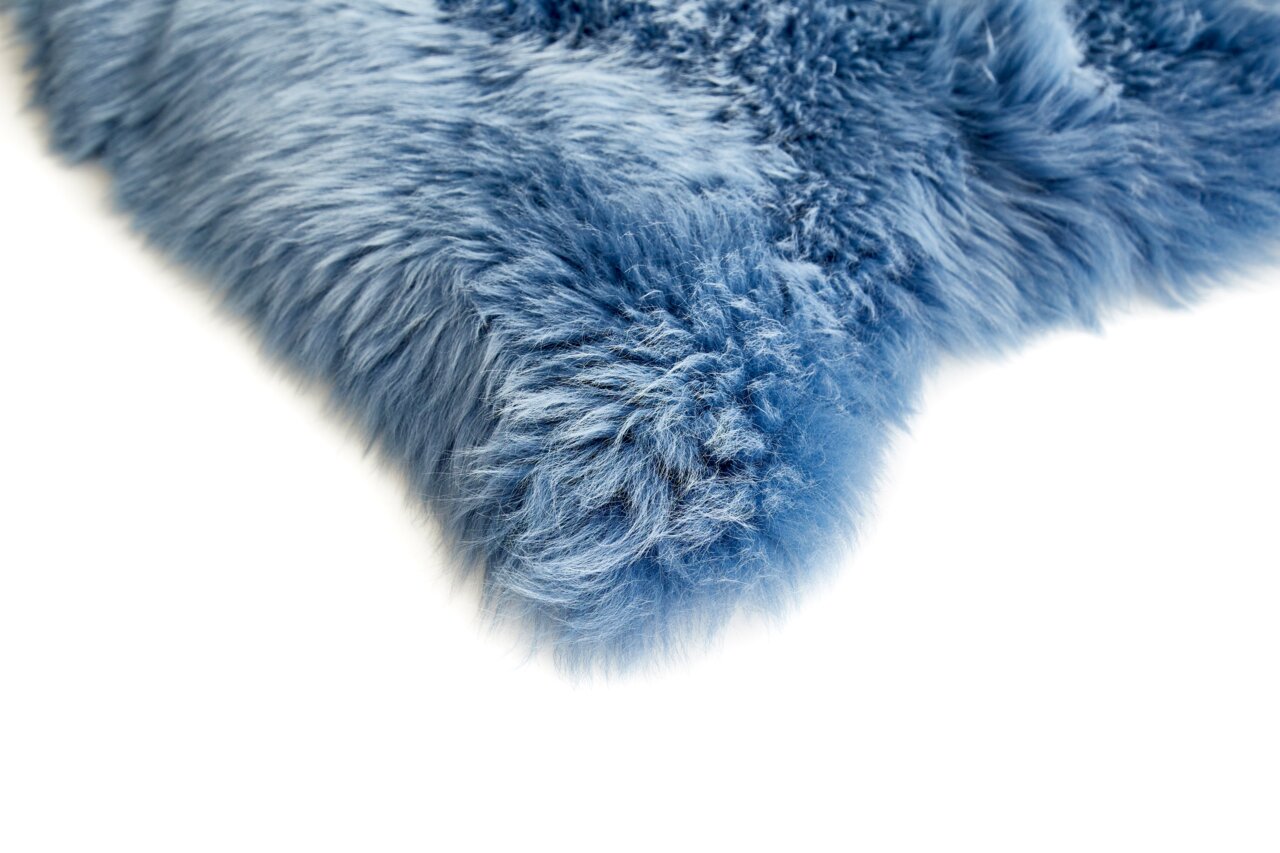 Close-up van een blauwe schapenvacht met een zachte, donzige textuur, gezien vanaf de zijkant.