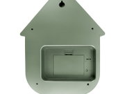 Achterkant van een groene wandklok in de vorm van een huisje, voorzien van een batterijvak en een ophangbeugel.