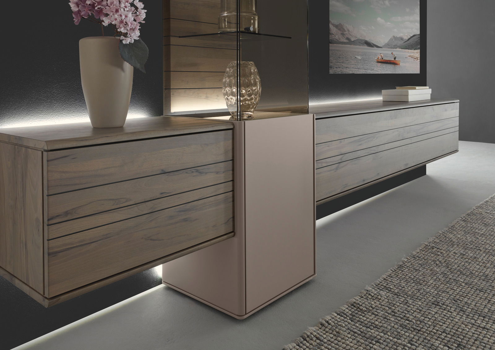 Moderne Wandkombination aus Holz mit integrierter Beleuchtung, seitliche Perspektive. Dekoriert mit einer Vase und einem Glasobjekt.