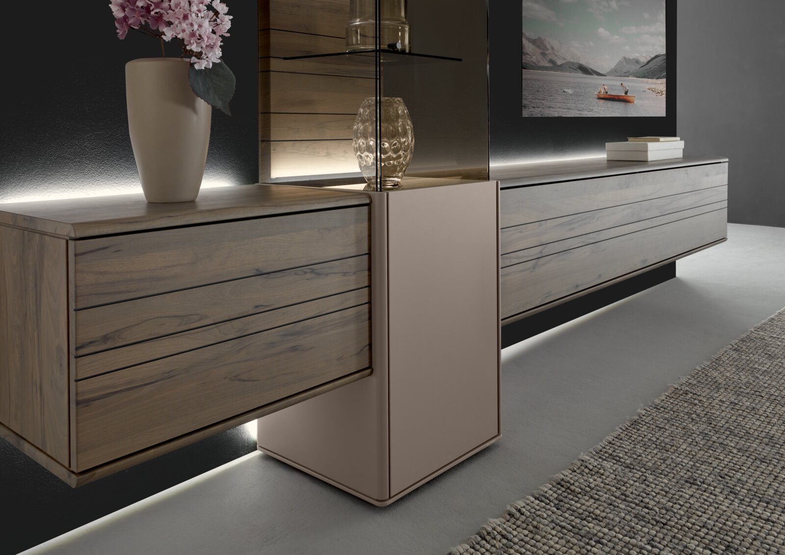 Moderne Wandkombination aus Holz mit integrierter Beleuchtung, seitliche Perspektive. Dekoriert mit einer Vase und einem Glasobjekt.