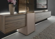 Moderne Wandkombination aus Holz mit integrierter Beleuchtung, seitliche Perspektive. Dekoriert mit einer Vase und einem Glasobjekt.