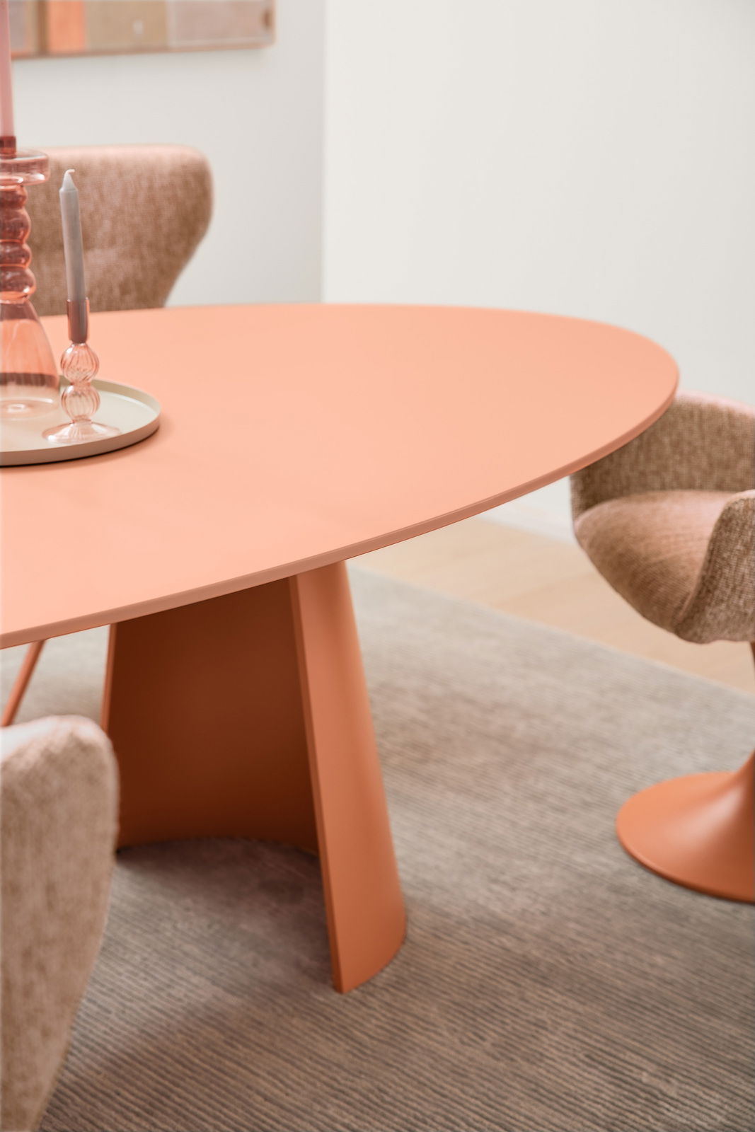 Runder Esstisch in warmem Terrakotta-Ton mit modernen Stühlen, seitliche Perspektive