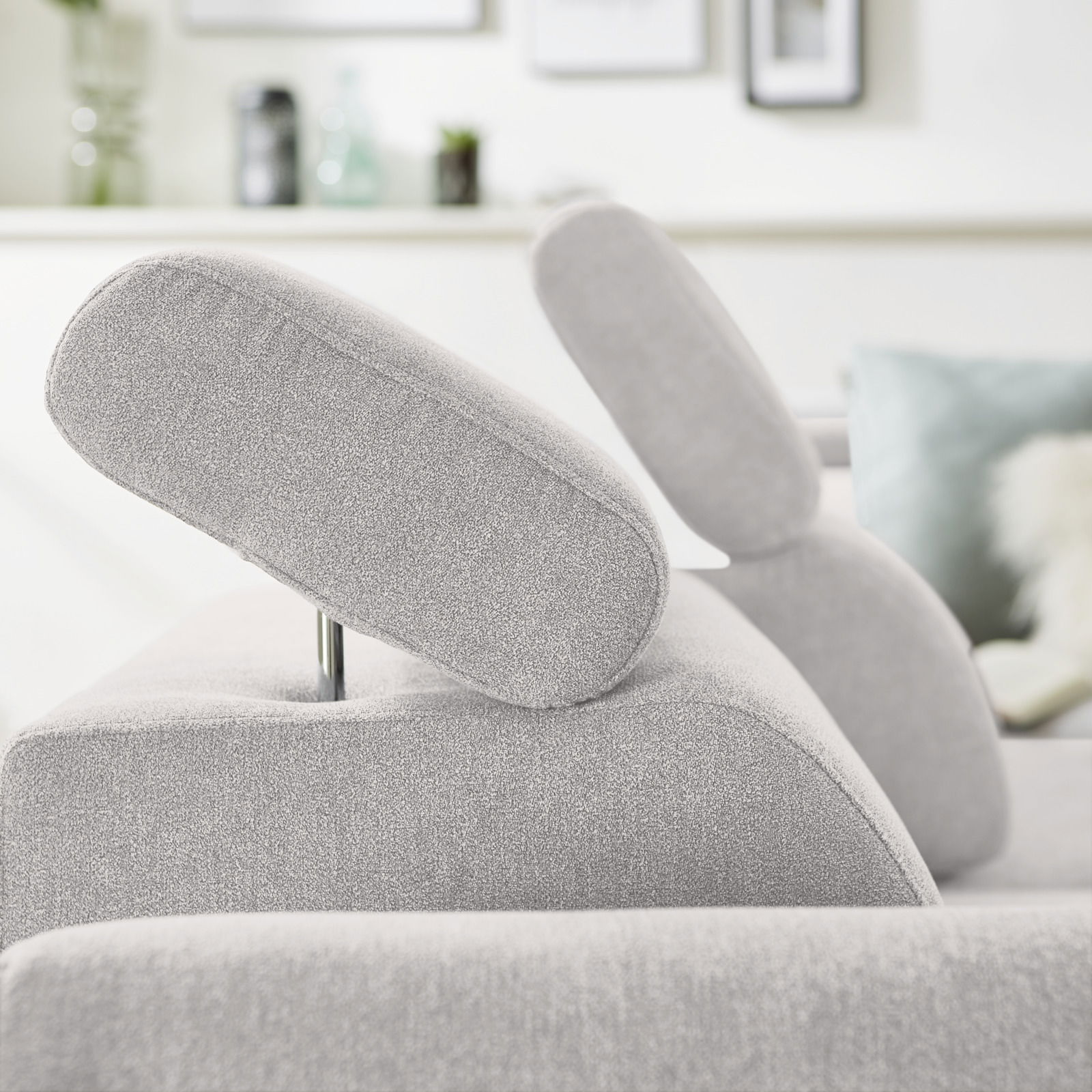 Nahaufnahme einer grauen Eckgarnitur mit verstellbaren Kopfstützen, seitliche Perspektive.