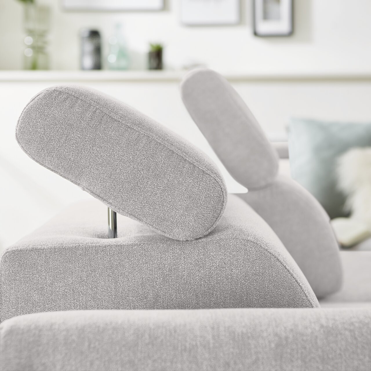 Nahaufnahme einer grauen Eckgarnitur mit verstellbaren Kopfstützen, seitliche Perspektive.