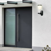 Moderne Akku-Außenwandleuchte an einer Hauswand neben einer Eingangstür, seitliche Perspektive