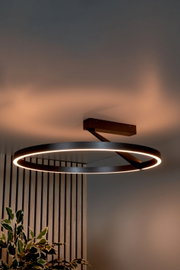 Moderne, ringförmige LED-Deckenleuchte in Schwarz mit warmweißem Licht, an rechteckiger Deckenhalterung befestigt; Perspektive: leicht von unten im Raumwinkel aufgenommen.