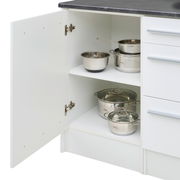 Kücheninsel mit geöffneter Schranktür, die Edelstahlkochtöpfe und -schüsseln auf zwei Regalböden zeigt, Perspektive von vorne.